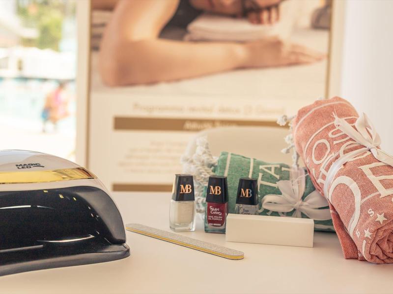 Set d'articles de soin avec lampe UV, serviette rose pliée, et petits flacons sur une table.