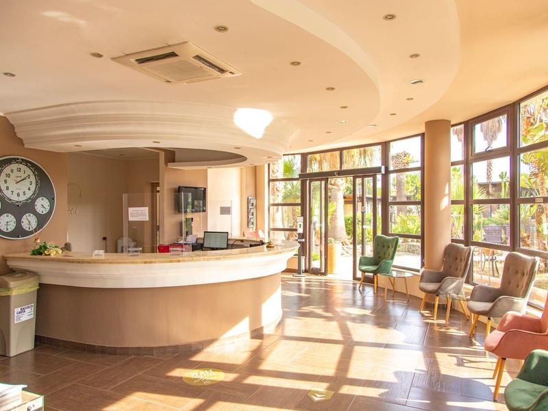 Réception d'hôtel moderne avec comptoir courbe et grandes fenêtres baignées de lumière.