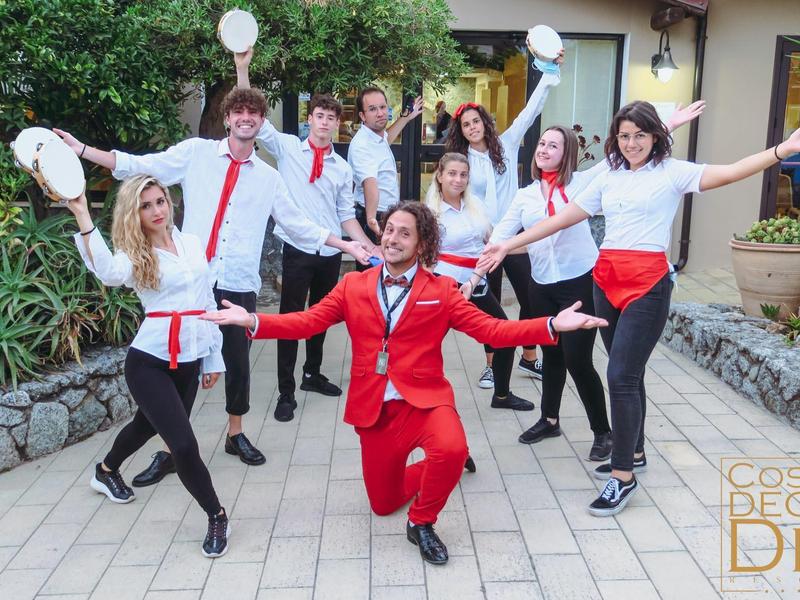 Groupe de serveurs souriants en uniforme rouge et blanc posant dans un patio extérieur.