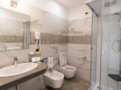 Modern bathroom with shower, sink, toilet, and bidet in neutral tones.