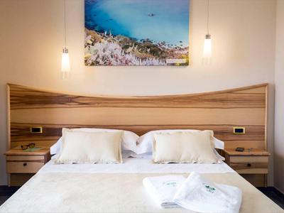 Chambre d'hôtel moderne avec lit double, tête de lit en bois et toile accrochée au-dessus du lit.