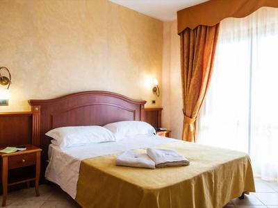 Cozy hotel room with double bed, nightstands, and large windows with curtains.