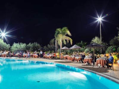 Piscine d'hôtel éclairée avec des invités et des palmiers la nuit