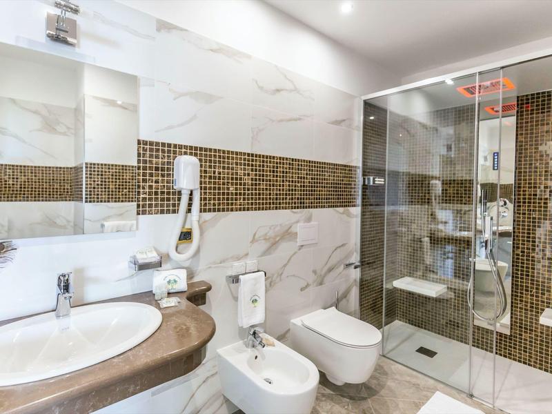 Salle de bain moderne avec lavabo, toilettes, bidet et douche vitrée.