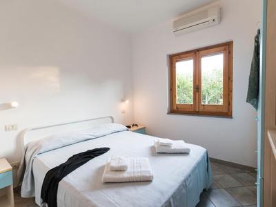 Sypialnia z podwójnym łóżkiem, białą pościelą, ręcznikami i oknem z widokiem na zieleń.