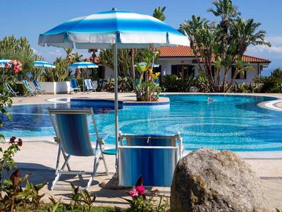 Niebieska parasolka i krzesło obok spokojnego basenu hotelowego w ogrodzie.