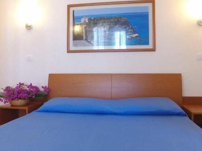 Une chambre simple avec un lit bleu, des tables de chevet et un tableau au mur.