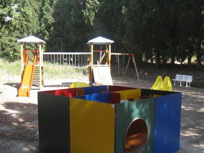 Aire de jeux colorée avec balançoires, toboggan et bac à sable en plein air.