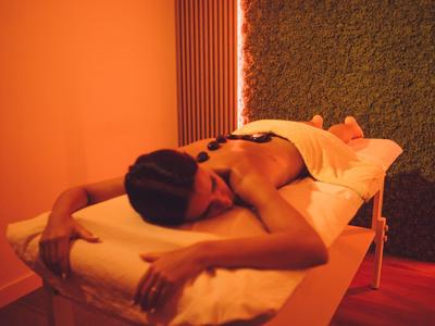 Femme allongée, détendue sur une table de massage dans une pièce éclairée chaleureusement.