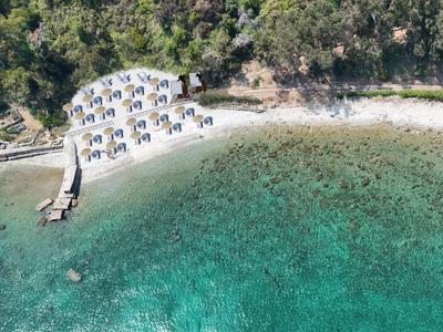 Vue aérienne d'une plage calme avec des transats et une eau turquoise claire.