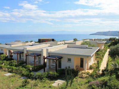 Alignement de bungalows avec vue sur la mer dans une station balnéaire sous un ciel bleu.
