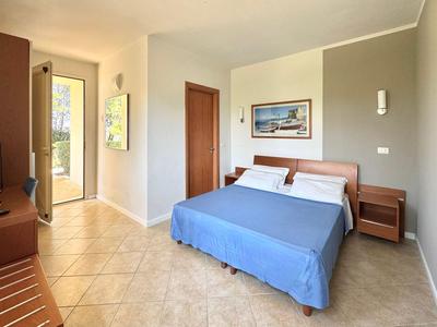 Modern hotel room with double bed, blue bedspread, and balcony access.