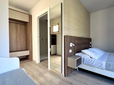 Modern hotel room with double bed, nightstands, and open wardrobe.