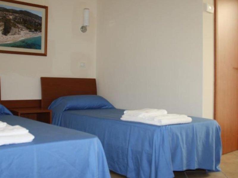 Chambre twin avec couvertures bleues et serviettes blanches, décor en bois simple.