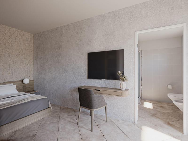 Chambre d'hôtel moderne avec lit, TV murale, bureau et chaise.