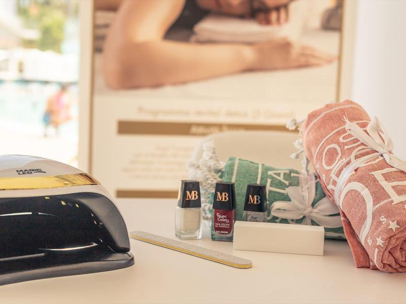 Produits de soins des ongles avec lampe LED, lime à ongles et serviette sur une table dans un salon.