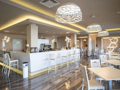 Modern interieur van een restaurant met wit meubilair en stijlvolle hanglampen aan het plafond.