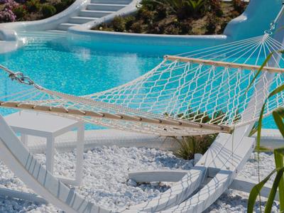 Hangmat naast een zwembad met waterglijbaan onder een heldere hemel.
