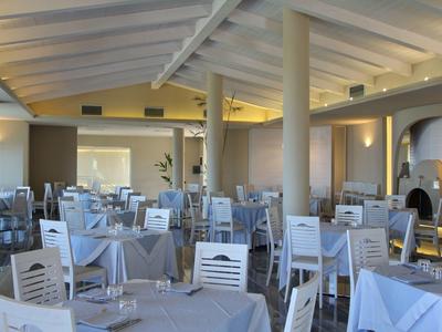 Licht hotelrestaurant met witte stoelen en gedekte tafels.