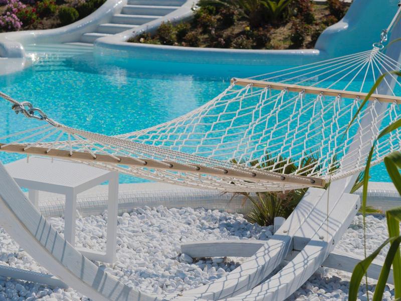 Hangmat naast een zwembad met waterglijbaan onder een heldere hemel.