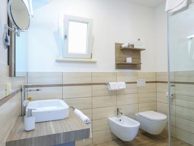 Modern bathroom with floating sink, wall-mounted toilet, bidet, and glass shower enclosure.