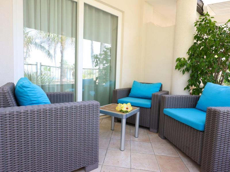 Outdoor patio with woven chairs and turquoise cushions around a small table with lemons.