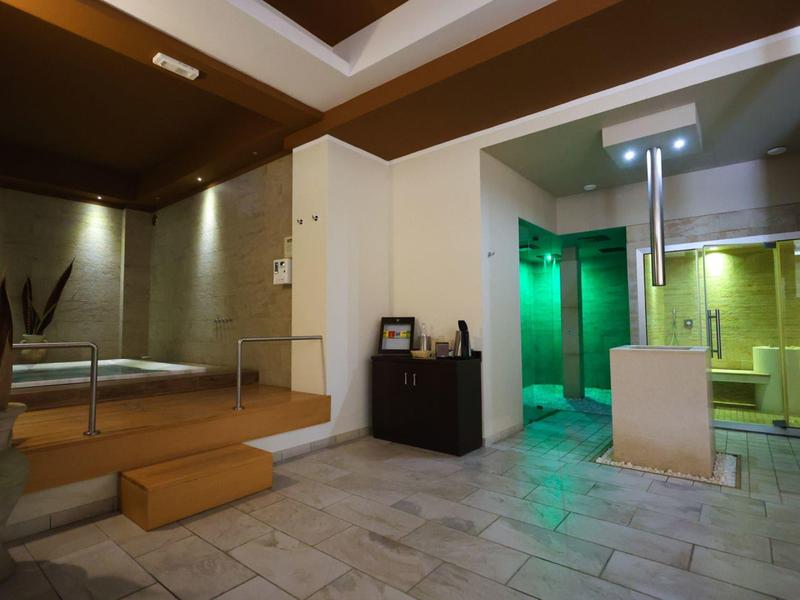 Modern spa area with seating, glass door, green lighting, and tiled flooring.