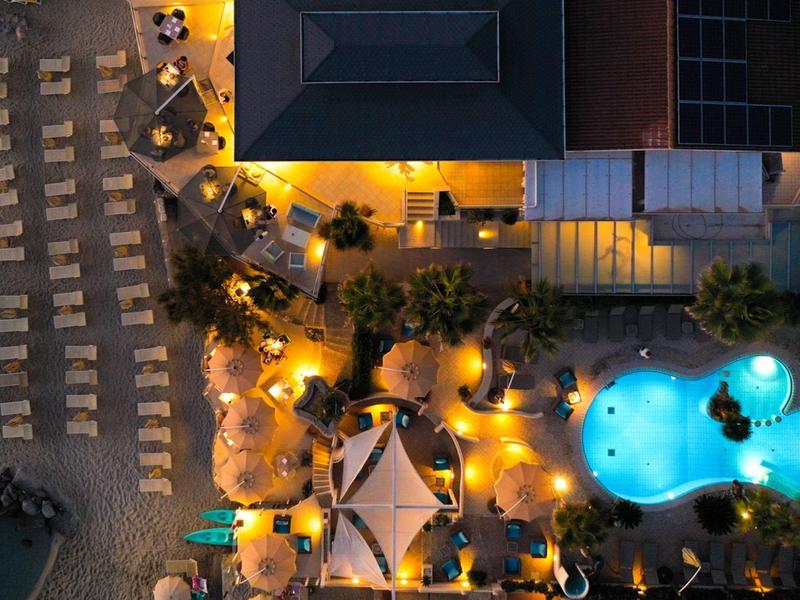Aerial view of a lit pool area and nearby beach loungers at night.