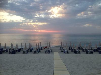Plage de sable avec rangées de chaises longues et parasols au coucher du soleil au bord de la mer