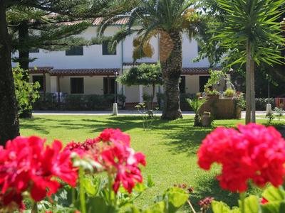 Jardin d'hôtel avec pelouses vertes, palmiers et fleurs rouges au premier plan.