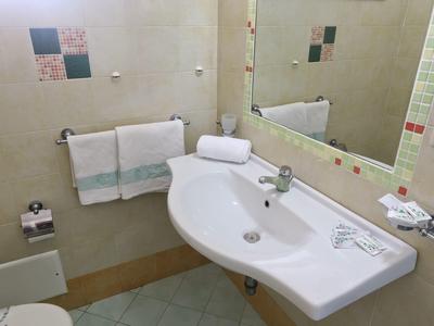 Salle de bain compacte avec lavabo blanc, miroir et serviettes blanches au mur.
