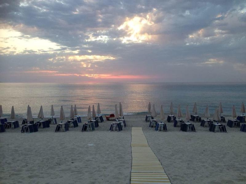 Plage de sable avec rangées de chaises longues et parasols au coucher du soleil au bord de la mer