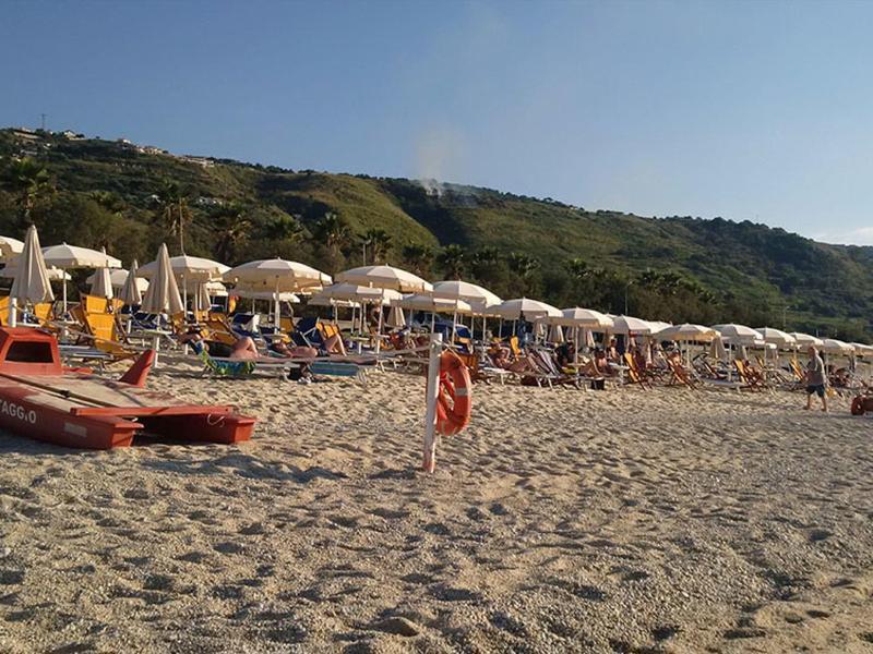 Plage avec sable, bateaux de sauvetage, parasols et montagnes en arrière-plan