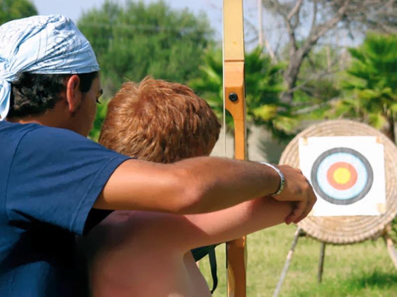 Deux personnes pratiquent le tir à l'arc en plein air devant une cible.