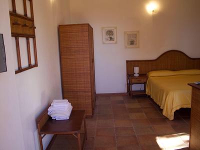 Schlichtes Schlafzimmer mit Holzmöbeln, gelber Bettdecke und fliesenboden.