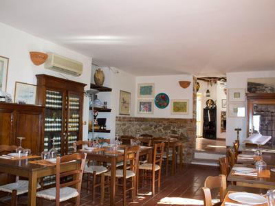 Innenansicht eines gemütlichen Restaurants mit Holzmöbeln, weißen Wänden und dekorativen Bildern.