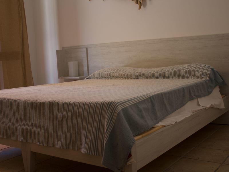 Schlichtes Schlafzimmer mit Doppelbett, hellen Holzmöbeln und braunen Vorhängen.