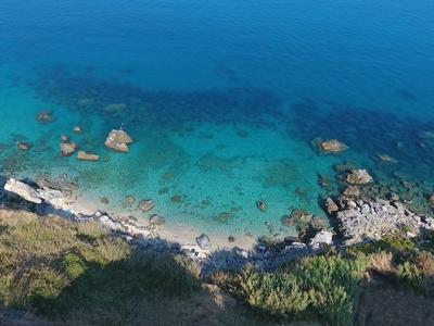 Mer turquoise claire sur côte rocheuse avec promeneurs et végétation verte