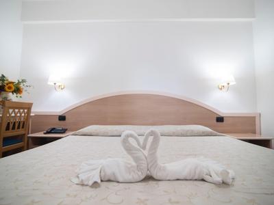 Chambre d'hôtel avec grand lit et cygne en serviette sur la couette.