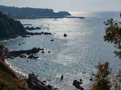Littoral avec falaises rocheuses et mer scintillante sous ciel nuageux.