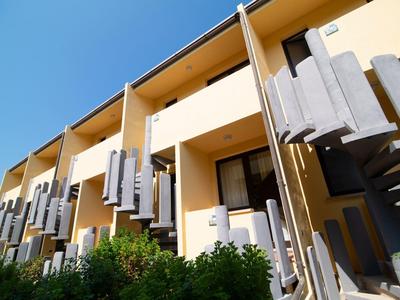 Architecture d'hôtel moderne avec peinture jaune et escaliers extérieurs en spirale sous un ciel dégagé.