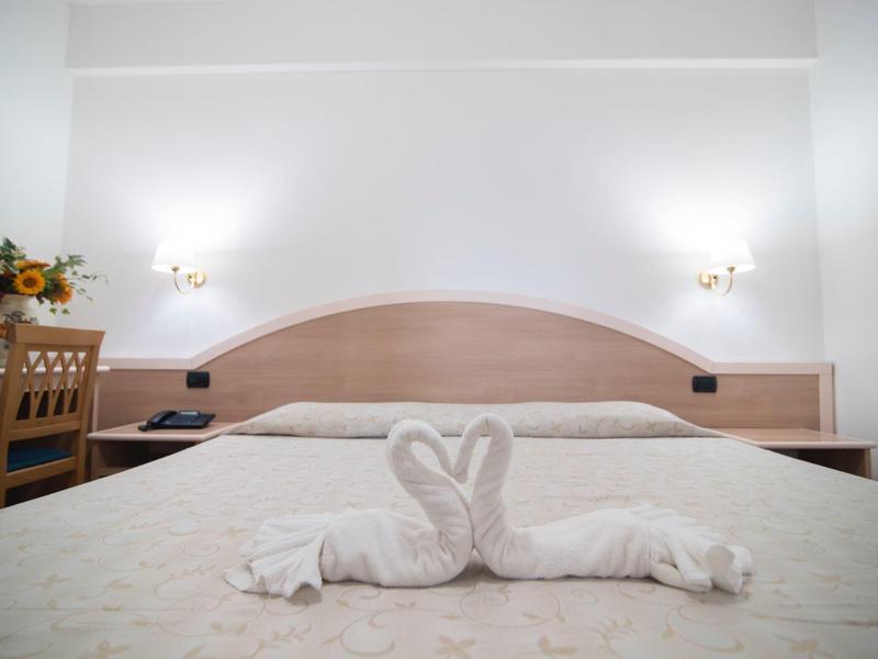 Chambre d'hôtel avec grand lit et cygne en serviette sur la couette.