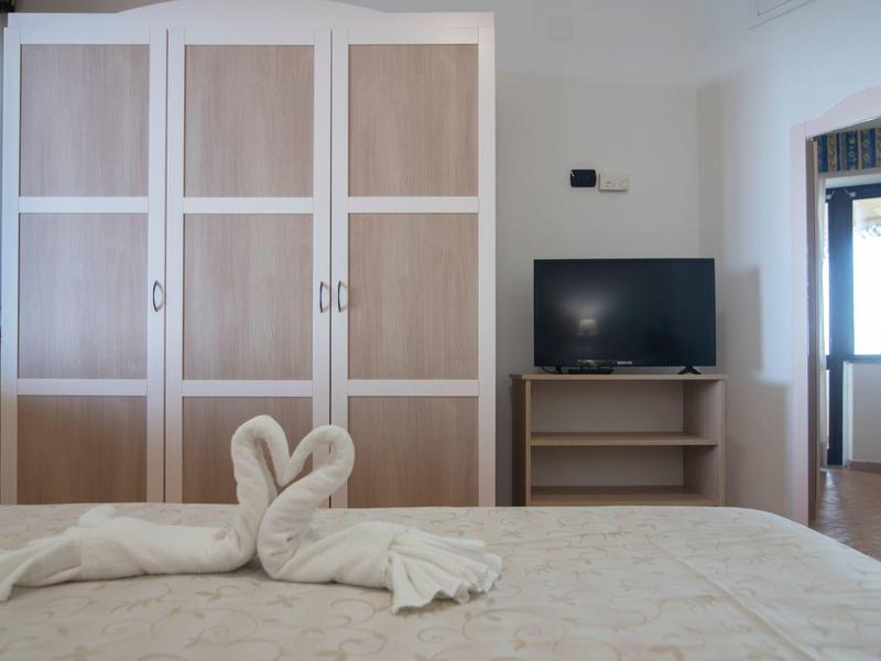 Chambre avec armoire, télévision et serviettes en forme de cygne sur le lit.