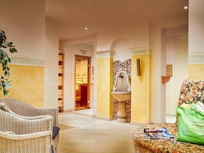 Helles Wohnzimmer mit gelb-weiß gestrichenen Wänden, Korbstühlen und Sofa mit Blumenmuster.