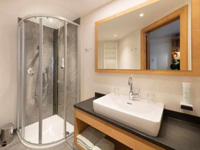 Modernes Badezimmer mit runder Dusche, großem Spiegel und rechteckigem Waschbecken auf Holzplatte.