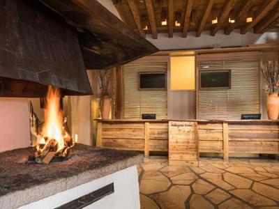 Gemütlicher Hotel-Loungebereich mit offenem Kamin und rustikalem Interieur.