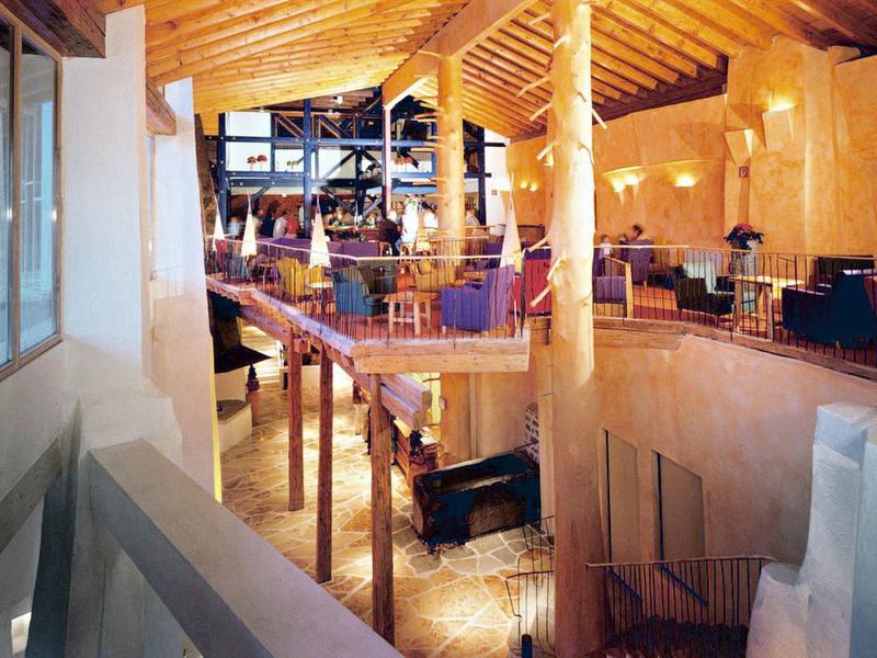 Großer, offener Innenraum mit Holzbalken, Säulen und einer Mischung aus moderner und rustikaler Einrichtung.