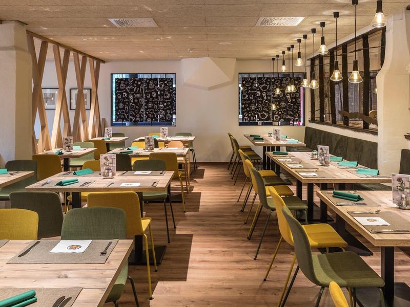 Gemütliches Restaurant mit Holzböden, grünen Stühlen und moderner Dekoration an den Wänden.