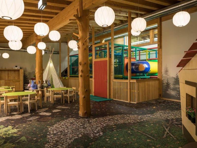 Kinderbereich mit Tischen, Bänken, Klettergerüst und buntem Spielbereich in einem Hotel.