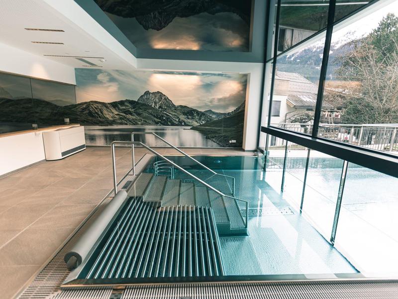 Moderner Innenpool mit Glasgeländer, Naturblick und heller, neutraler Raumgestaltung.